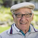 Laechender Senior mit Brille und Mütze