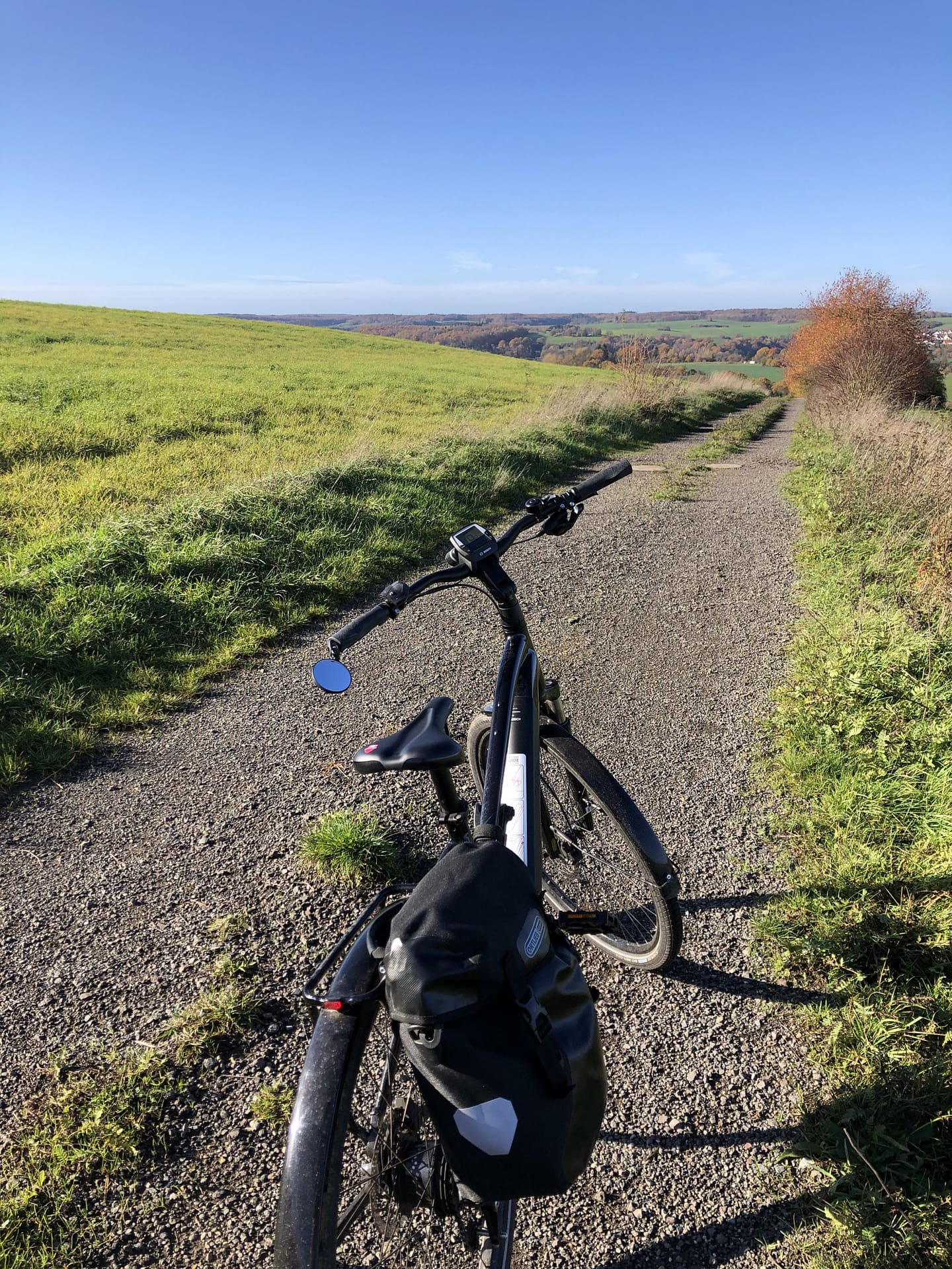E-Bike auf Feldweg mit grünen Wiesen und blauem Himmel